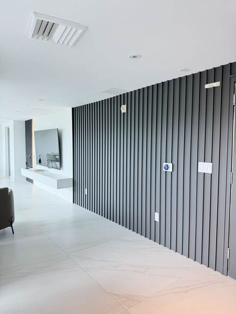 Full-height black vertical slat accent wall along a condo hallway