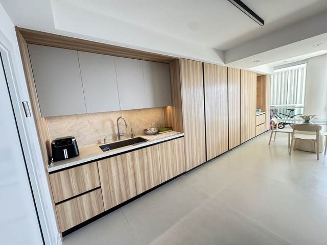 Light oak handleless kitchen with full-height pantry cabinetry and stone backsplash
