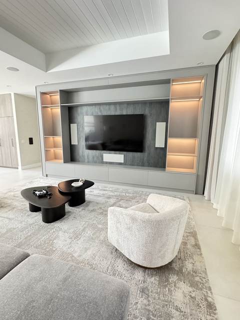 Backlit gray media wall with recessed niches and integrated TV